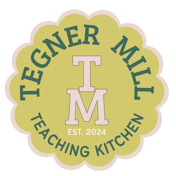 Logo for Tegner Mill Teaching Kitchen with a green 'TM' and text on a yellow background